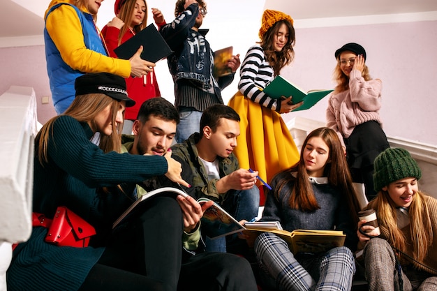 O grupo de estudantes alegres, sentado em uma sala de aula antes da lição.