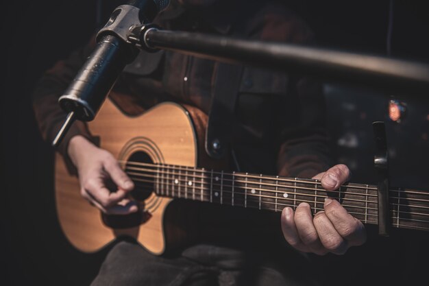 O guitarrista toca violão com um capo na frente de um microfone