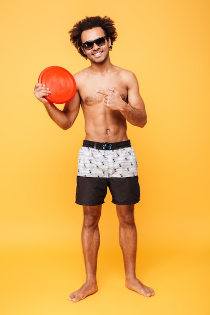 Foto grátis o homem africano novo de sorriso que guarda a praia brinca e apontar.