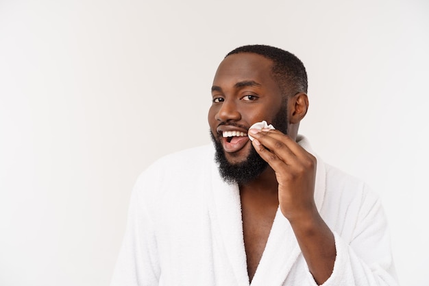 O homem africano sorridente aplica a limpeza do conceito de cuidados com a pele do homem do rosto