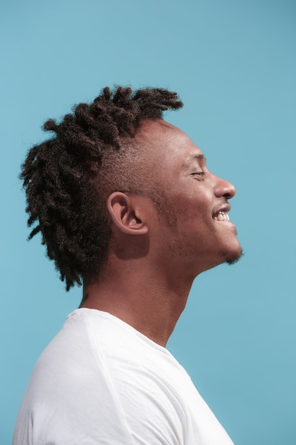 Foto grátis o homem afro-americano de negócios feliz em pé e sorrindo contra um fundo azul. vista de perfil.