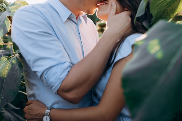 O homem alegre e a mulher gravida abraçam-se mutuamente em pé estar no campo