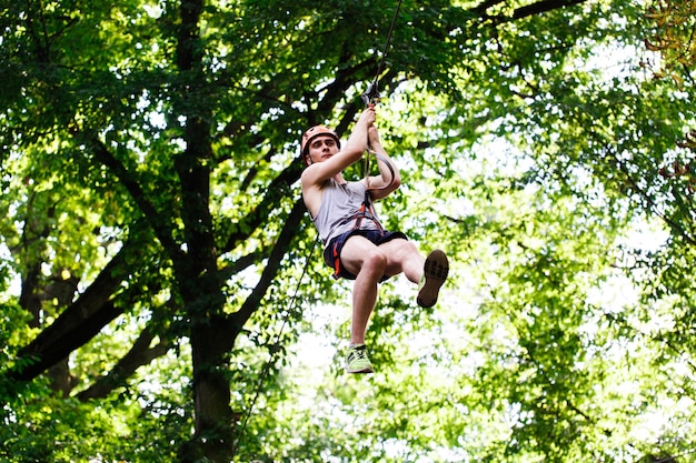 O homem cai na corda em um parque de entretenimento