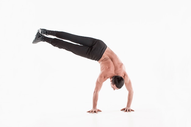 O homem caucasiano acrobático de ginástica posando em postura de equilíbrio