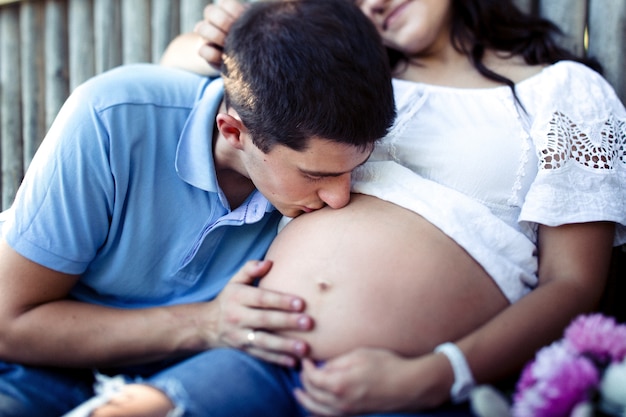 O homem charmoso beija a barriga gemea macia de sua dama com camisa branca