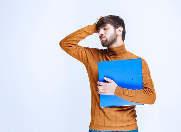 O homem com uma pasta azul parece cansado e com sono.