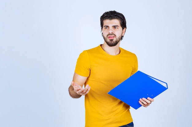 O homem com uma pasta azul parece confuso ou inexperiente.