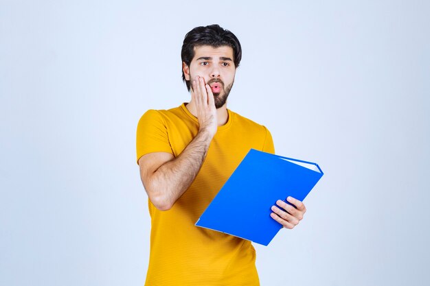 O homem com uma pasta azul parece confuso ou inexperiente.