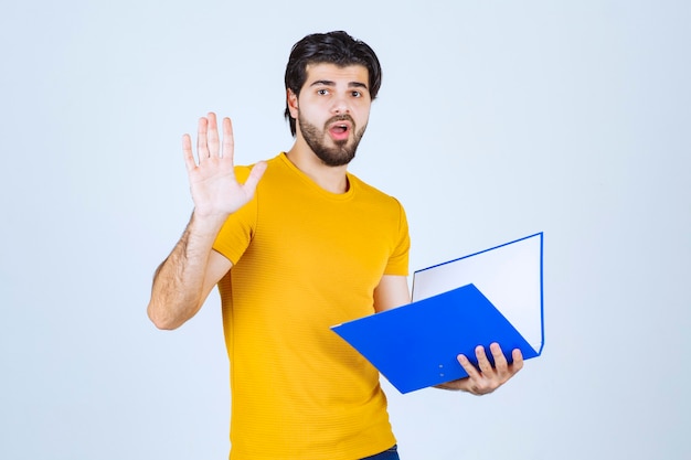 O homem com uma pasta azul parece confuso ou inexperiente.