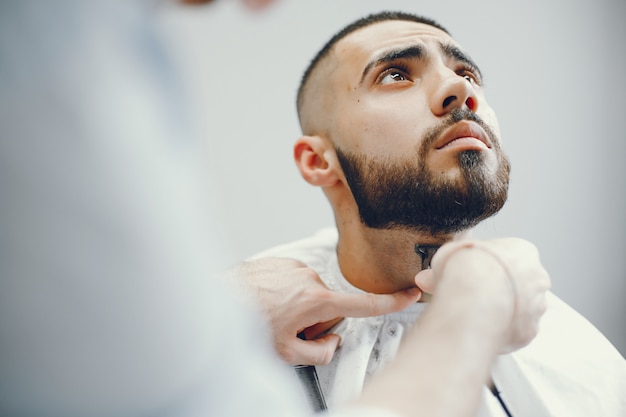 O homem corta a barba na barbearia.