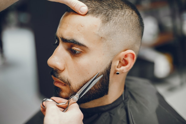 O homem corta a barba na barbearia.