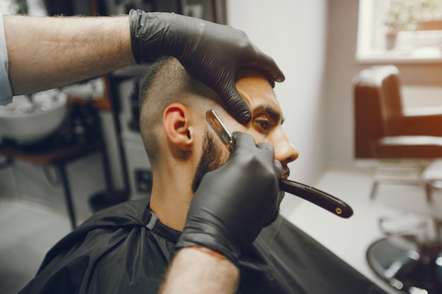 O homem corta a barba na barbearia.