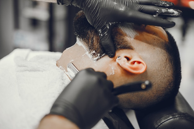 O homem corta a barba na barbearia.