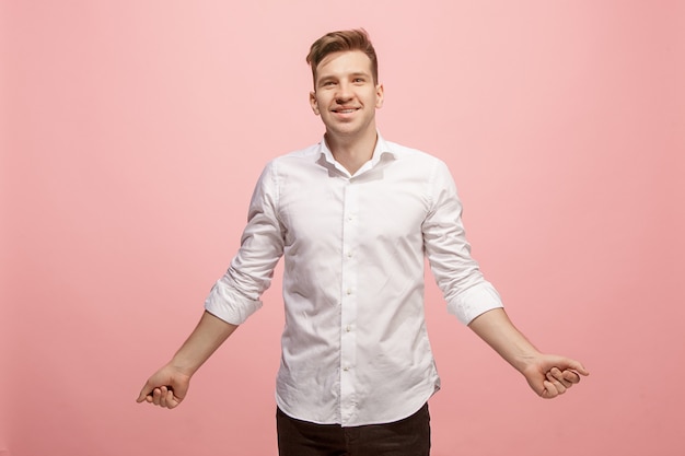 Foto grátis o homem de negócios feliz em pé e sorrindo contra fundo rosa.