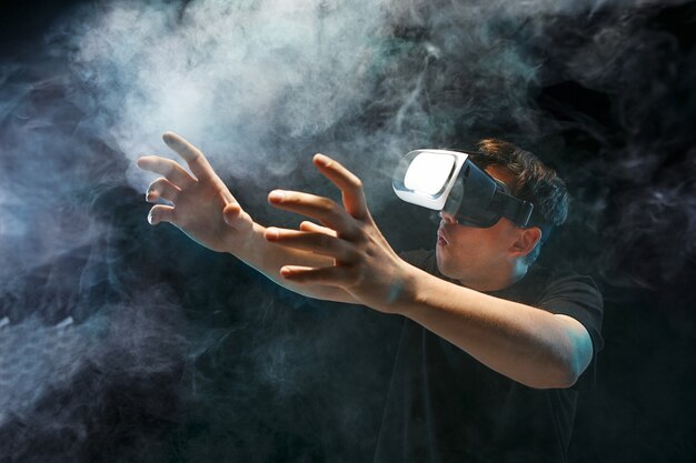 O homem de óculos de realidade virtual. Conceito de tecnologia do futuro. Fumarento preto do estúdio