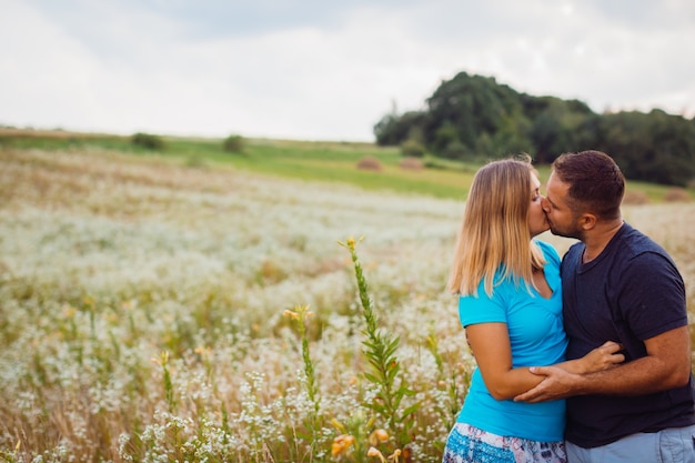O homem e a mulher se beijam um ao outro em pé no campo