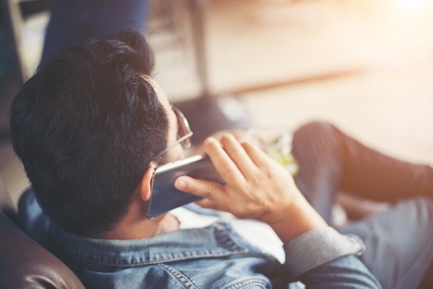 O homem novo com smartphone sorriso que relaxa no café.