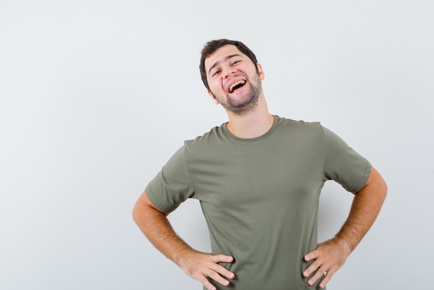 O homem rindo está colocando as mãos na cintura no fundo branco