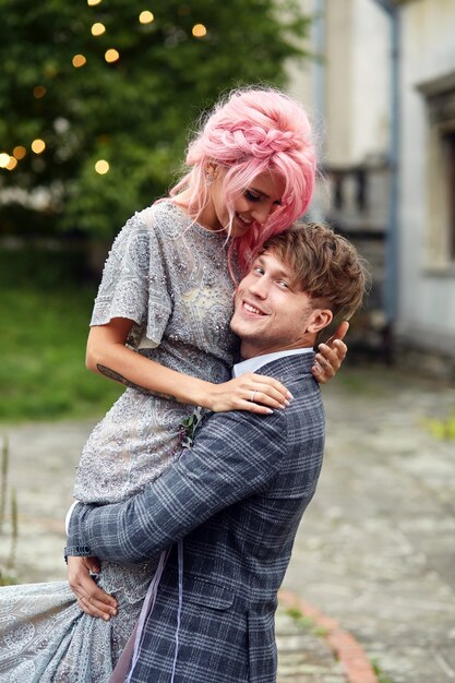 O homem segura a mulher com cabelo rosa de pé contra o vento