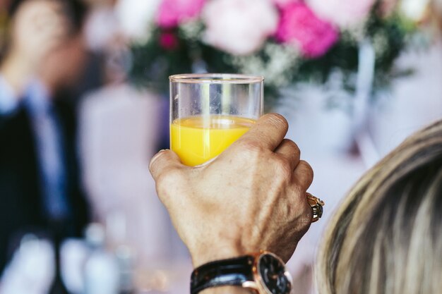 O homem segura um copo de suco de laranja