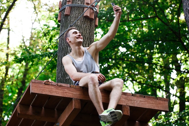 O homem toma selfie sentado na árvore