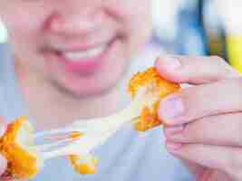 Foto grátis o homem vai comer bola de queijo frito estiramento pegajoso.