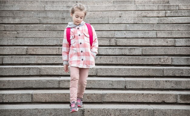 O início das aulas e o primeiro dia do outono. Uma doce menina está no contexto de uma grande escadaria larga.