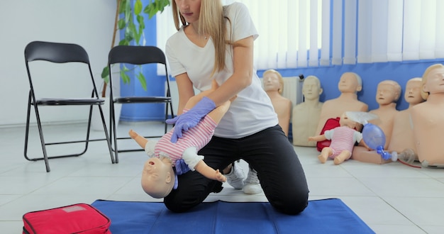 O instrutor realiza a rcp em uma boneca de treinamento para bebês. instrutora mostra como fazer rcp em uma boneca para treinamento de reanimação cardiopulmonar.