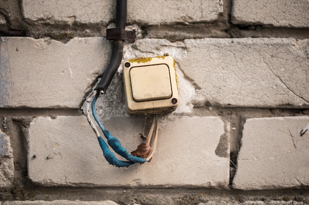 O interruptor antigo na parede de tijolos torceu a fita azul.