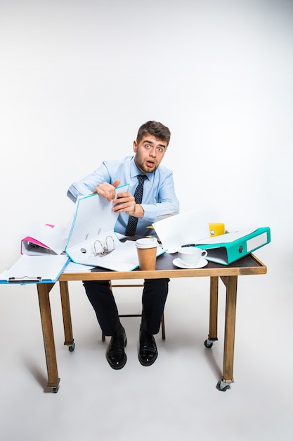 Foto grátis o jovem bagunça o ambiente de trabalho, não consegue organizar seu espaço e encontrar documentos importantes. conceito de problemas do trabalhador de escritório, negócios, publicidade, problemas diários.