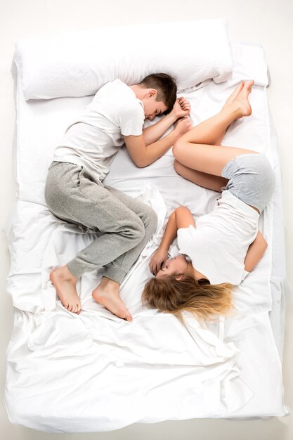 O jovem casal adorável, deitado em uma cama