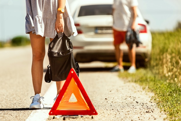 O jovem casal quebrou o carro durante uma viagem para descansar. Eles estão tentando parar outros motoristas e pedir ajuda ou pedir carona. Relacionamento, problemas na estrada, férias.