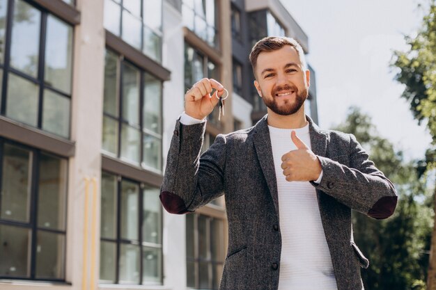 O jovem com as chaves acaba de comprar um apartamento novo