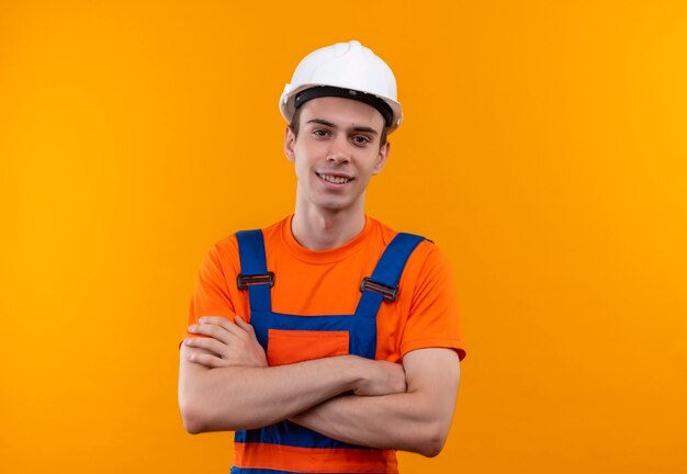 O jovem construtor vestindo uniforme de construção e capacete de segurança sorri