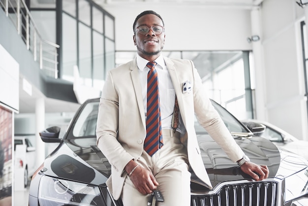O jovem empresário negro e atraente compra um carro novo, sonhos realizados.