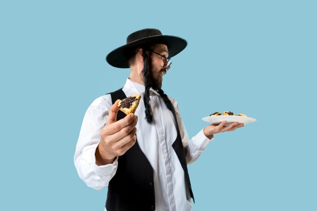 O jovem judeu ortodoxo com chapéu preto e biscoitos Hamantaschen para o festival judaico de Purim