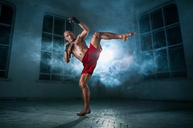 O jovem kickboxing na fumaça azul