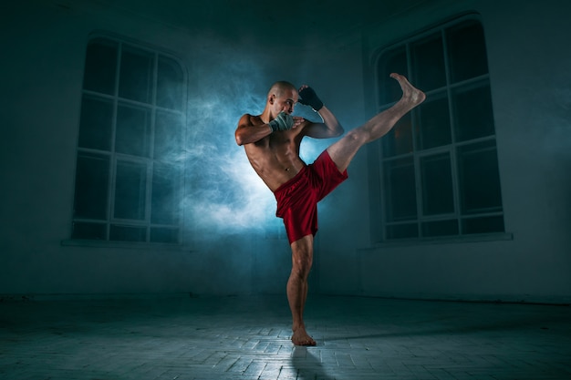 O jovem kickboxing na fumaça azul