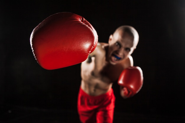 O jovem kickboxing no preto com kapa na boca