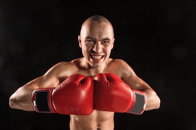 O jovem kickboxing no preto com uma cara gritando