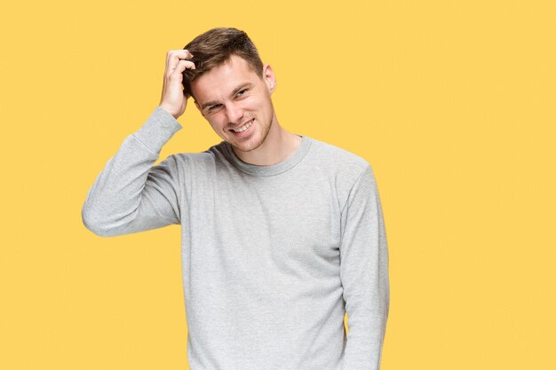 O jovem sorrindo e olhando para a câmera no fundo amarelo do estúdio