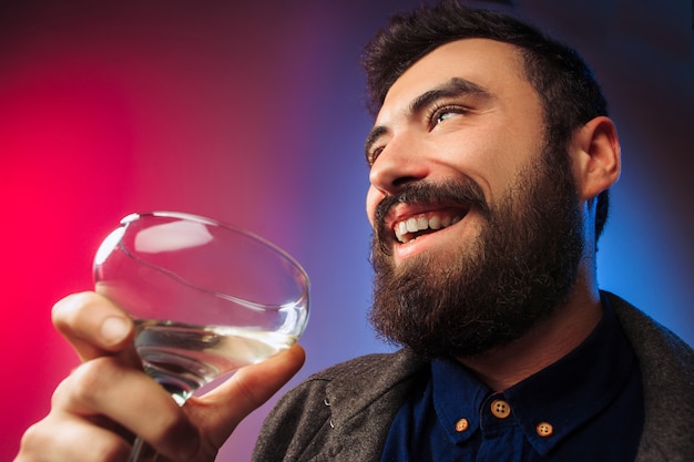 O jovem surpreso posando com um copo de vinho.