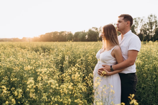 O lindo casal apaixonado abraçando e permanente no campo