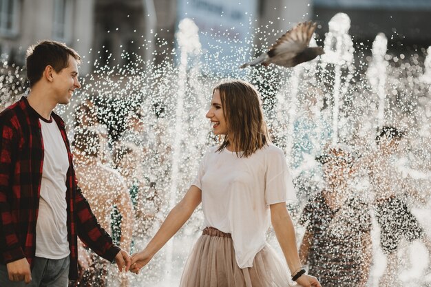 O lindo casal apaixonado andando perto da fonte