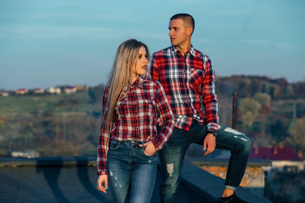 O lindo casal apaixonado em pé no telhado