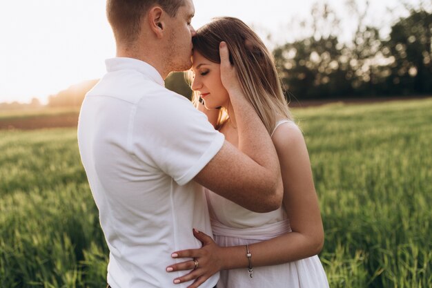 O marido beijando sua esposa e de pé no campo