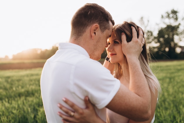 O marido beijando sua esposa e de pé no campo