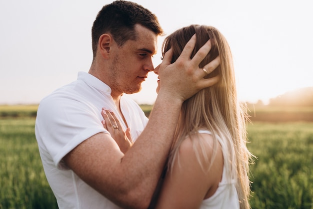 O marido beijando sua esposa e de pé no campo