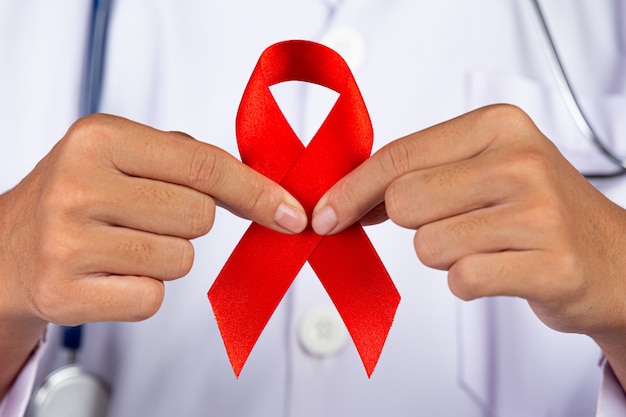 O médico possui uma fita vermelha, conscientização sobre o hiv, dia mundial da aids e dia mundial da saúde sexual.