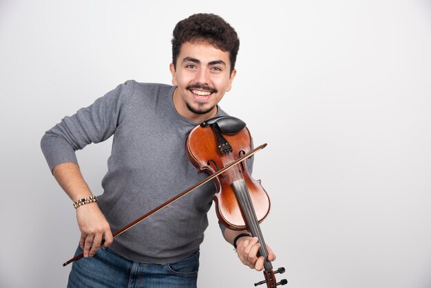O músico toca violino e parece inspirado e positivo.